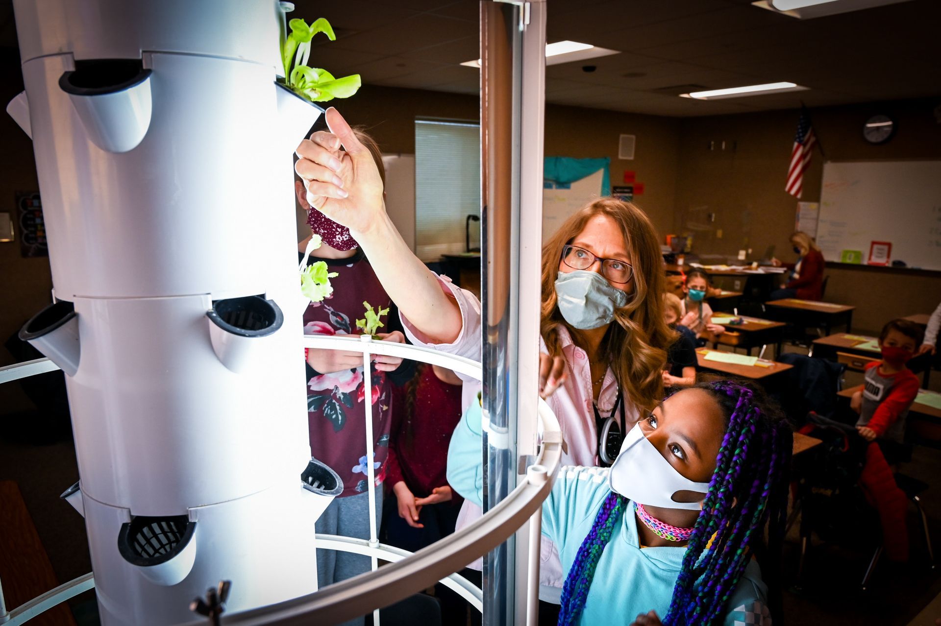 A woman is teaching a girl how to grow plants in a classroom.