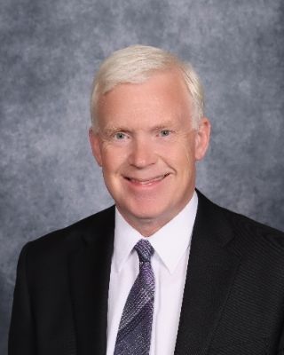 A man in a suit and tie is smiling for the camera.