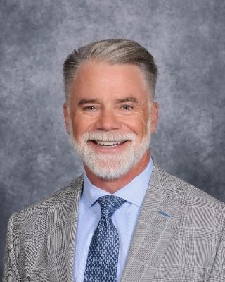 A man in a suit and tie is smiling for the camera.