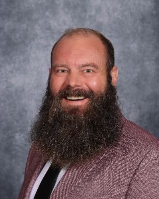 A man with a beard is wearing a pink sweater.