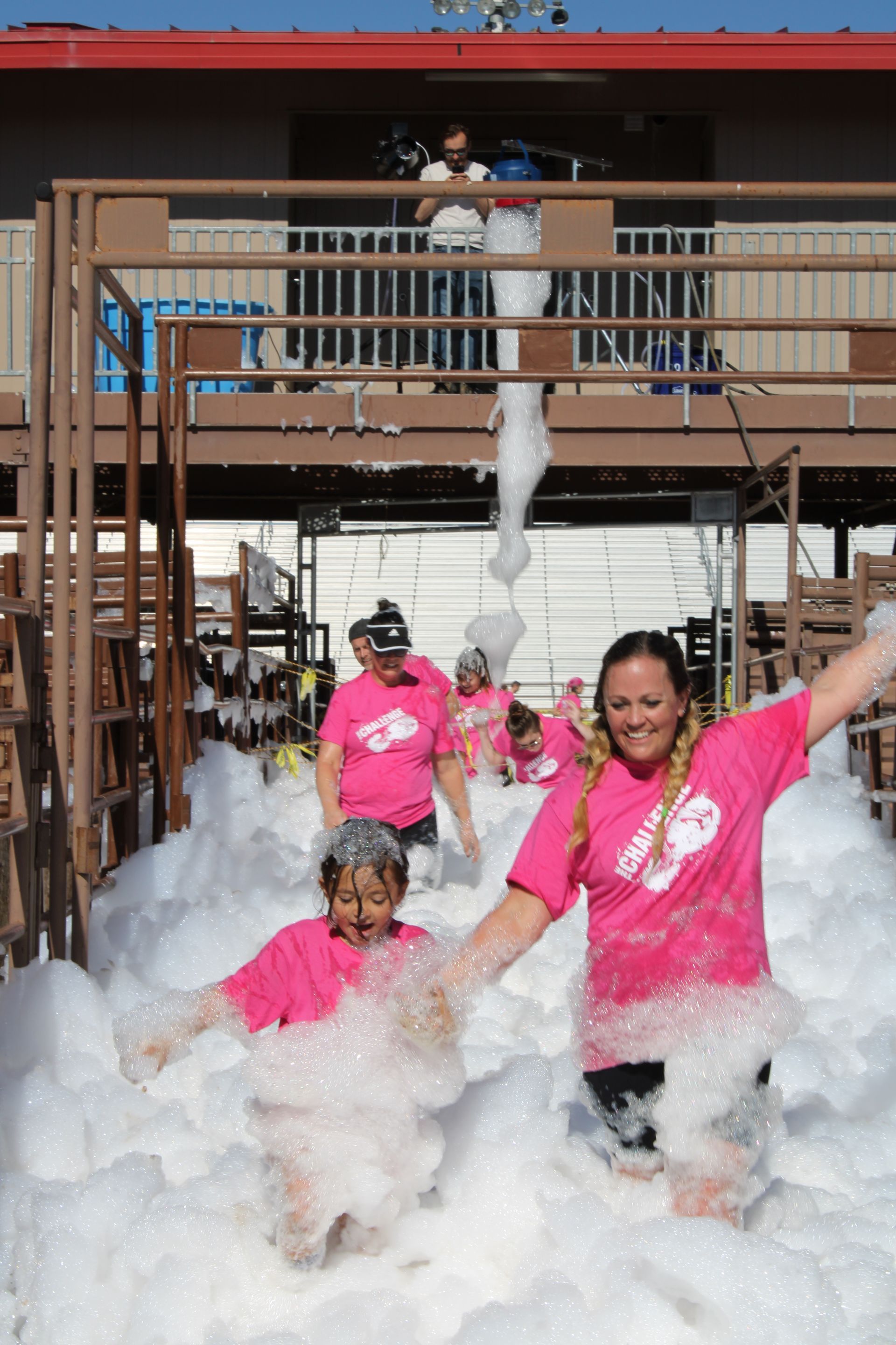 A group of people in pink shirts are playing in a pool of foam.