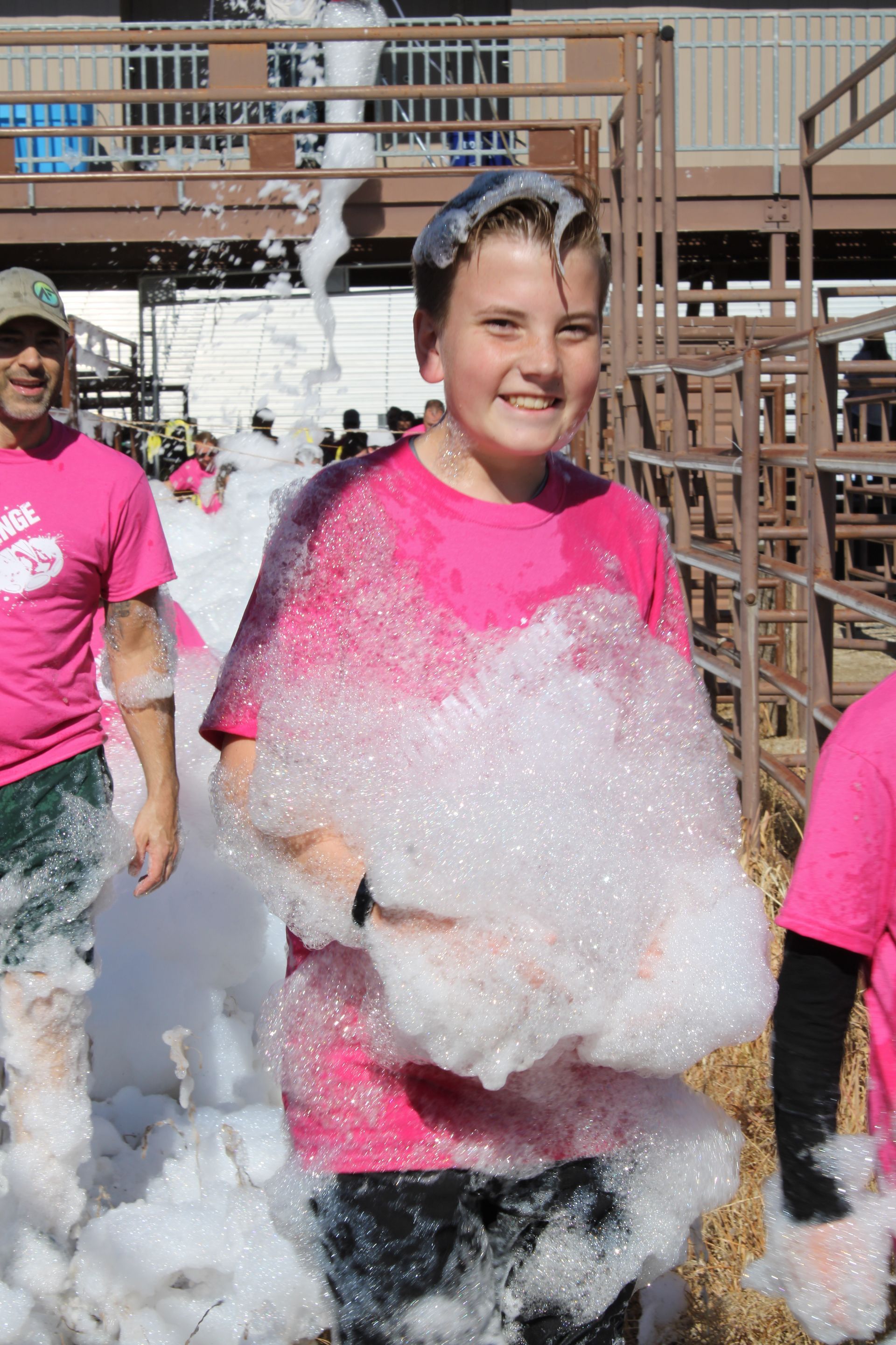 A boy in a pink shirt is covered in foam