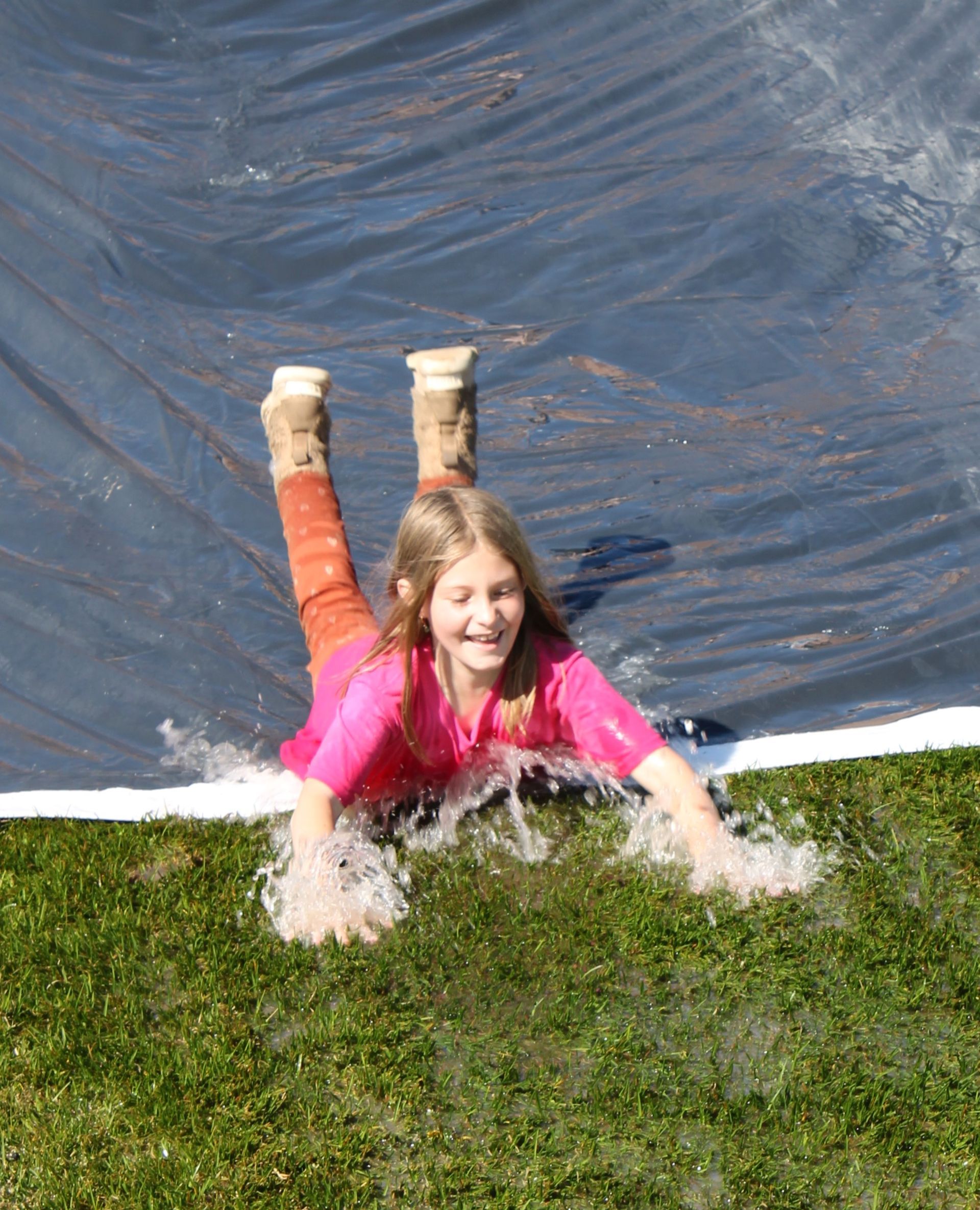 A young girl is sliding down a water slide.