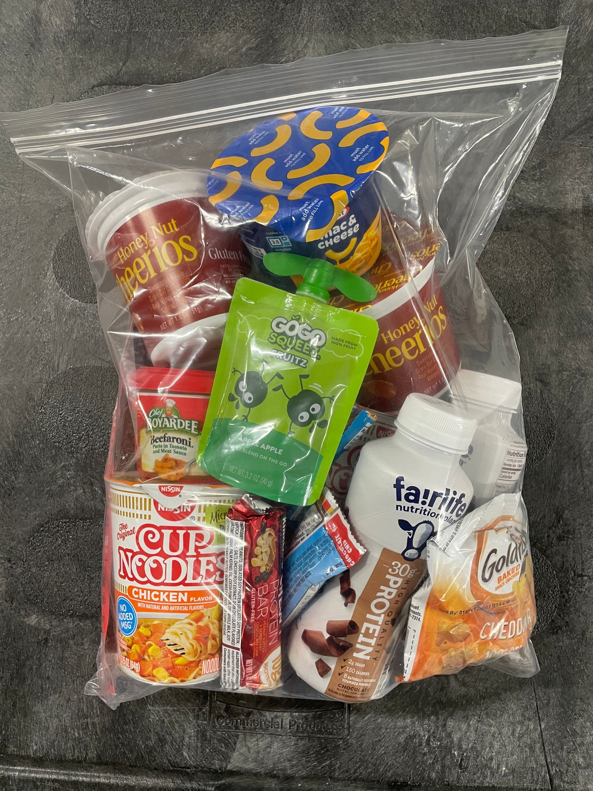 A bag of snacks including goldfish , maruchan instant lunch chicken , and chewy candy.