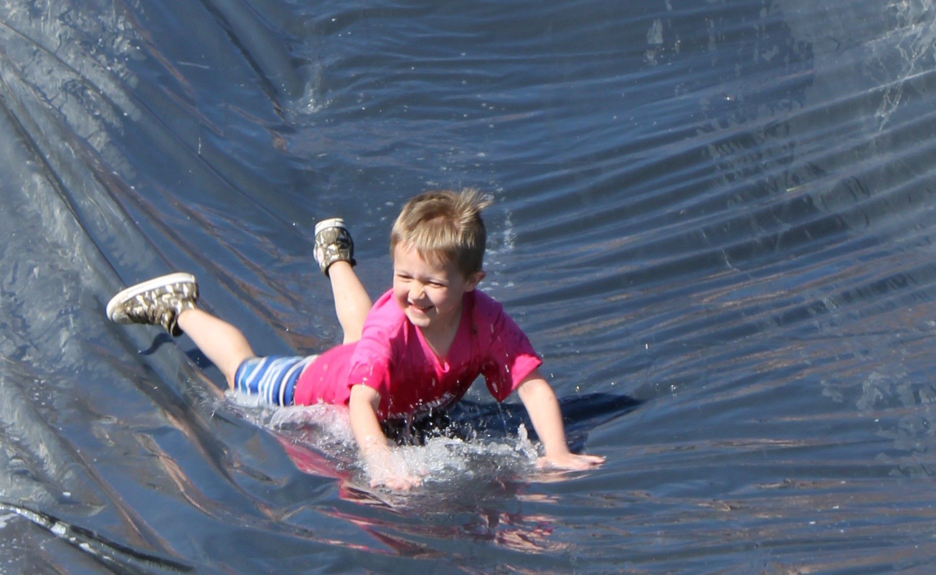 A young boy is sliding down a water slide.
