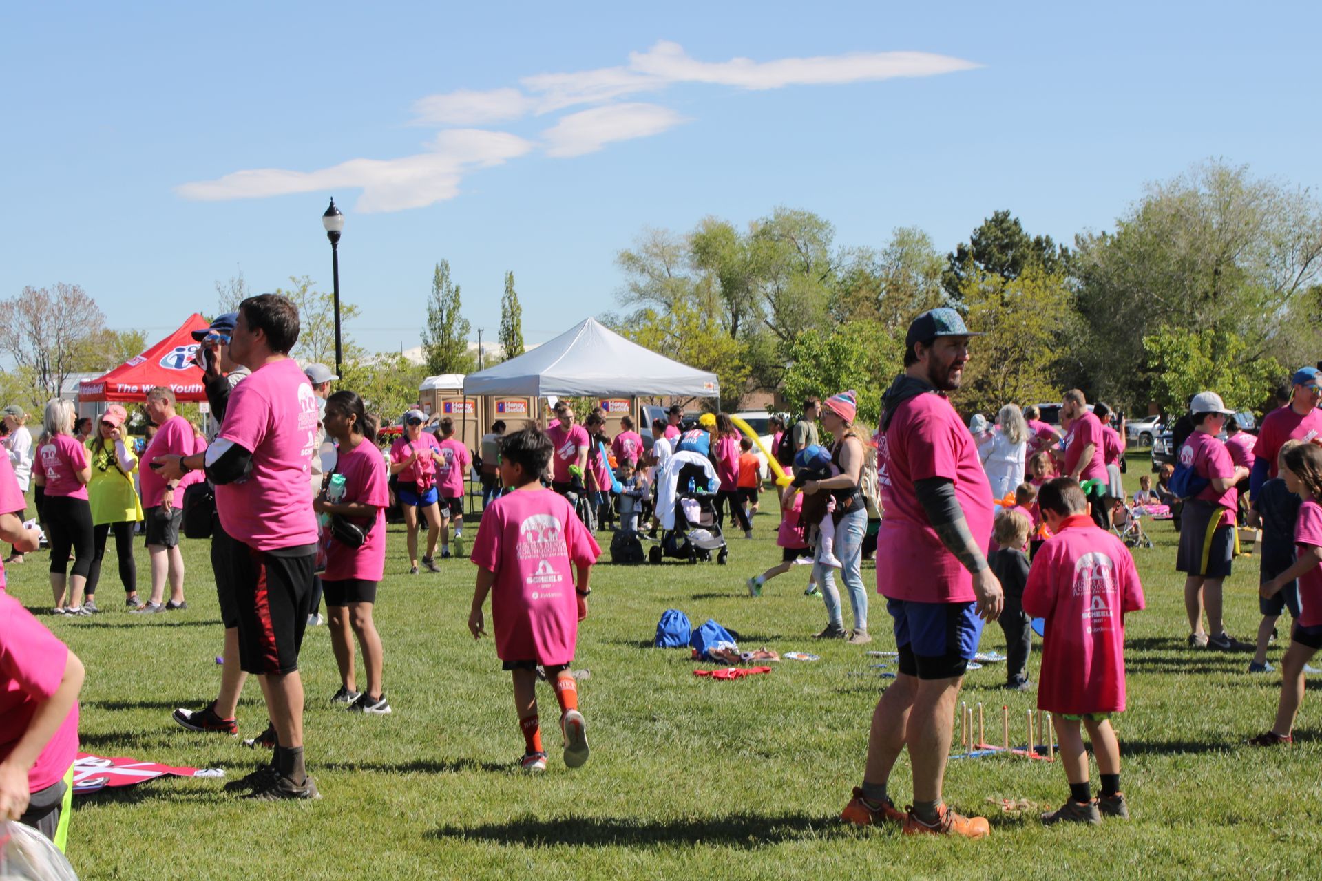 A group of people in pink shirts are standing in a field.