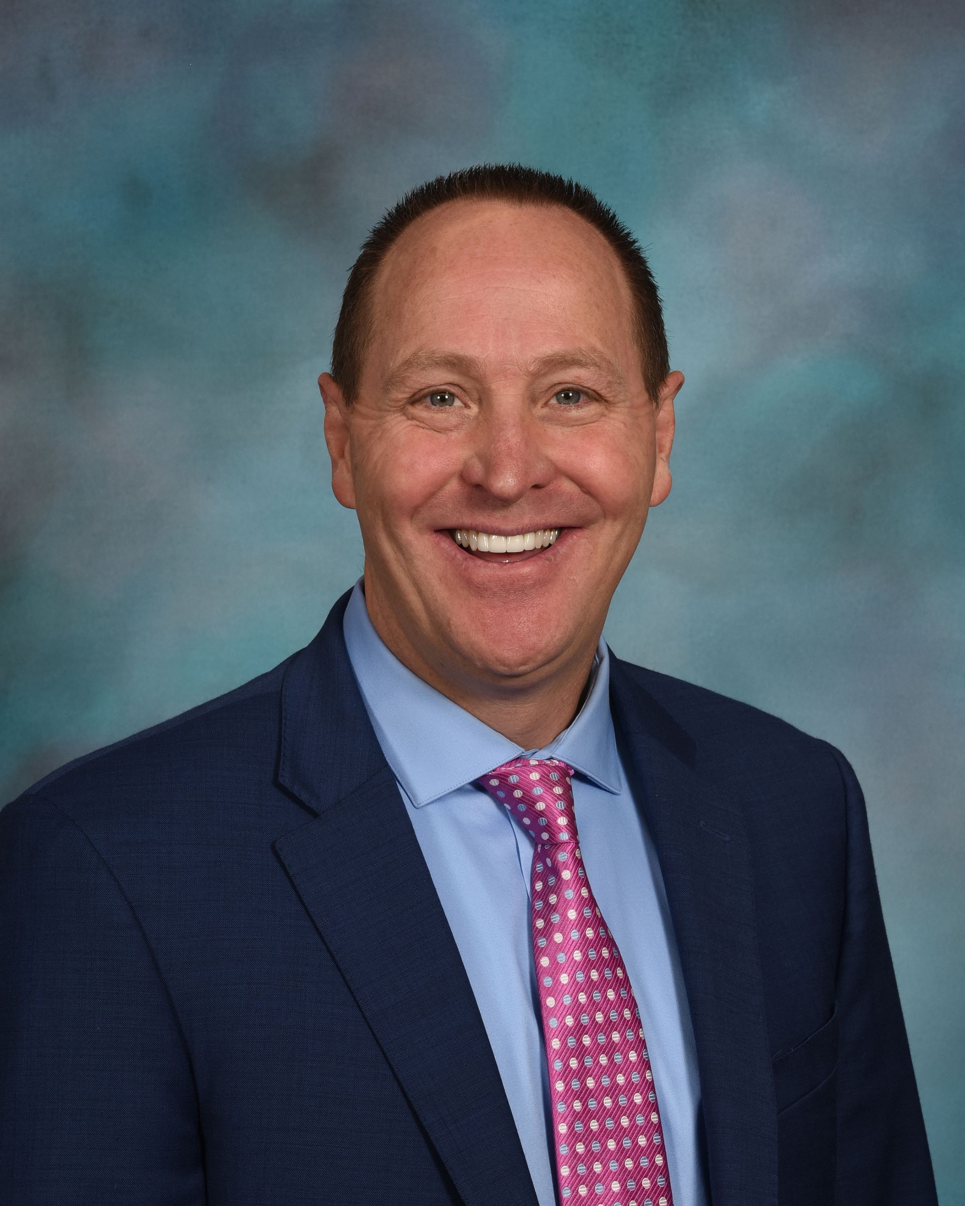A man in a suit and tie is smiling for the camera.