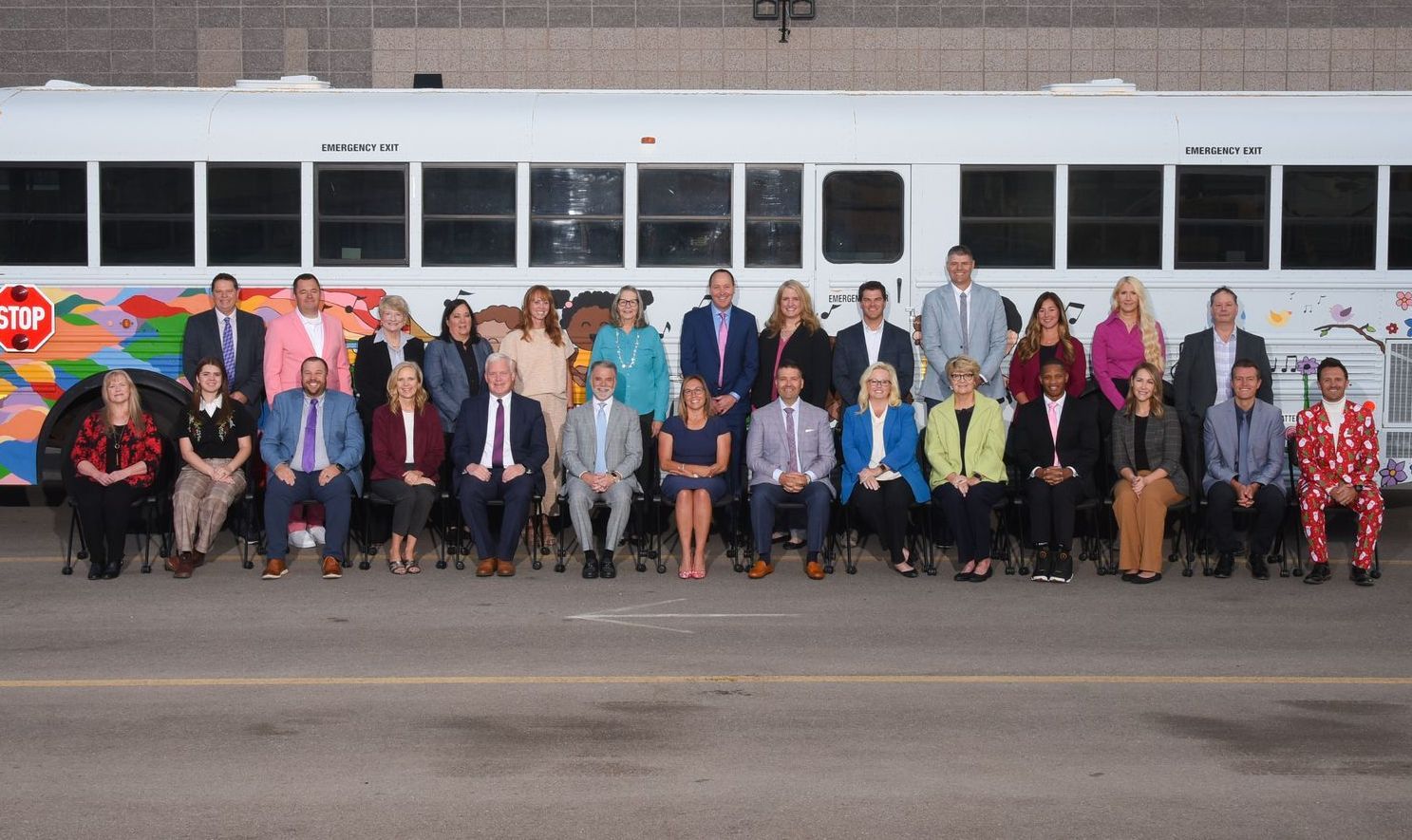 A large group of people are posing for a picture in front of a bus.