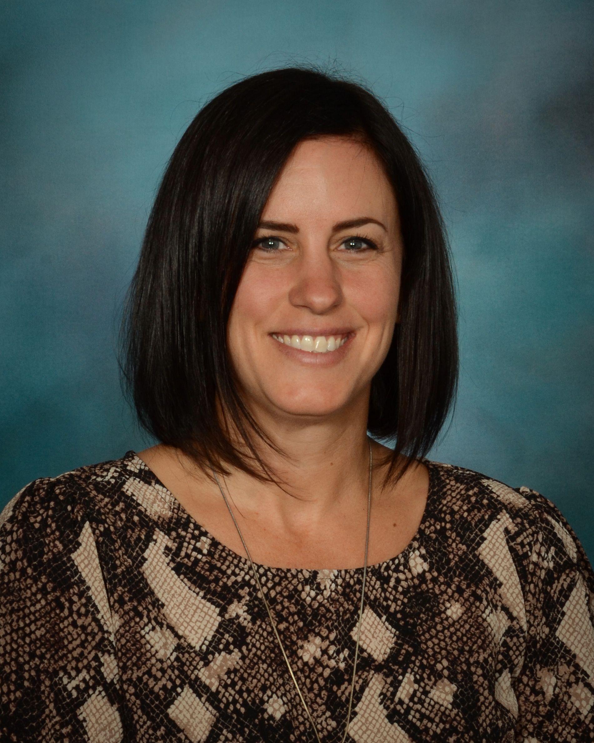 A woman in a snake print shirt is smiling for the camera.