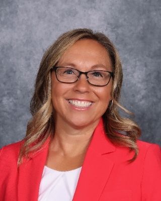 A woman in a pink jacket is smiling for the camera.