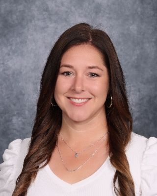 A woman in a red jacket and black shirt is smiling for a picture.