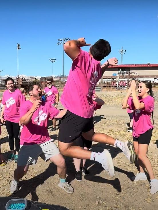 A group of people in pink shirts are jumping in the air