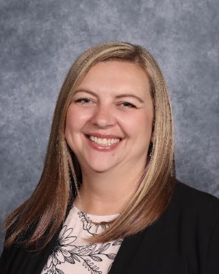 A woman in a blue shirt is smiling for a picture.