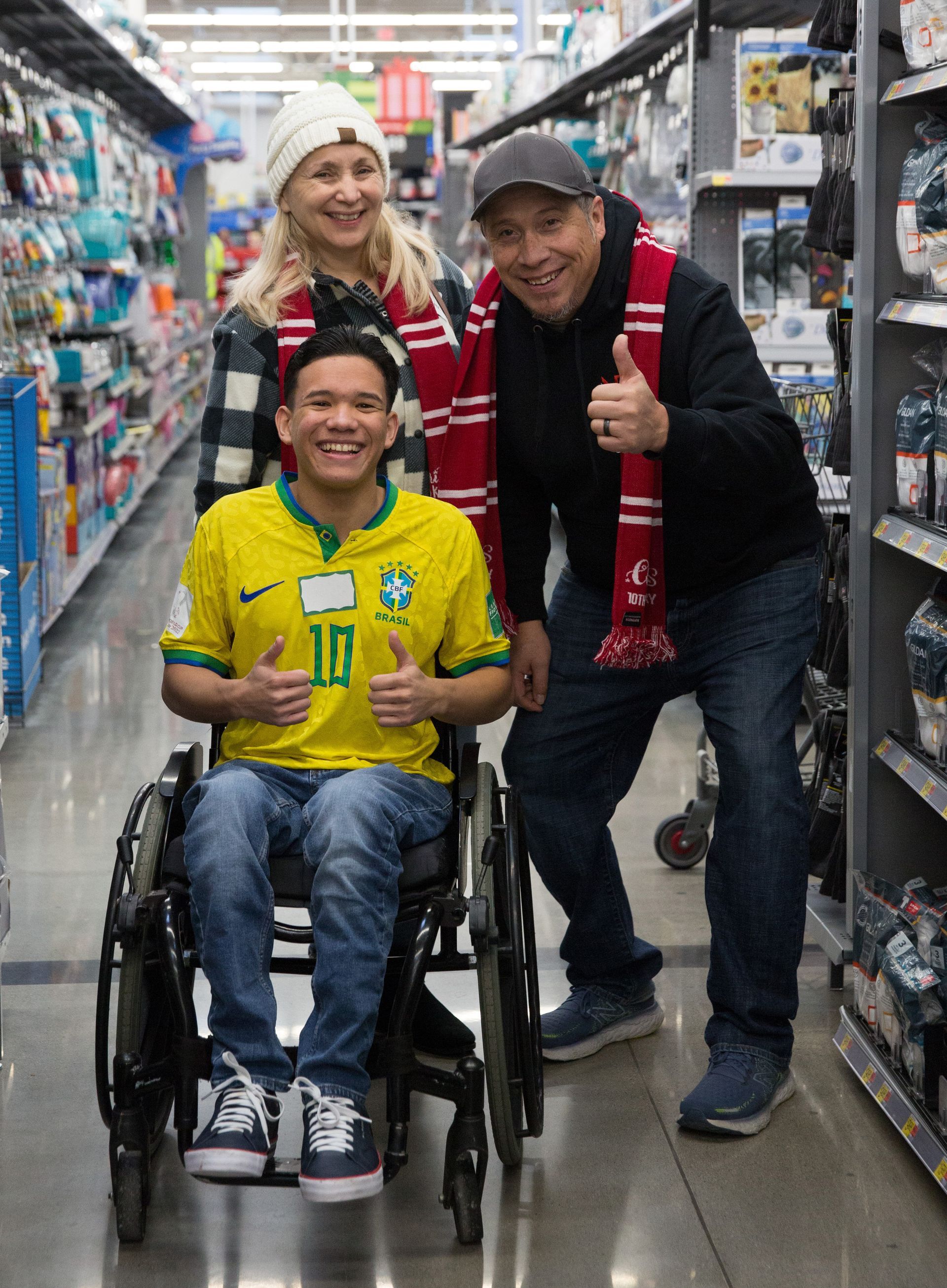 A man in a wheelchair is posing for a picture with two people in a store.