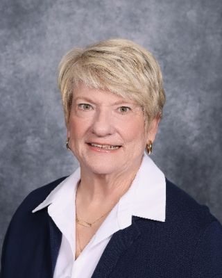 A woman in a suit and striped shirt is smiling for the camera.