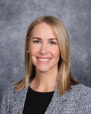 A woman is smiling for a picture in front of a blue background.