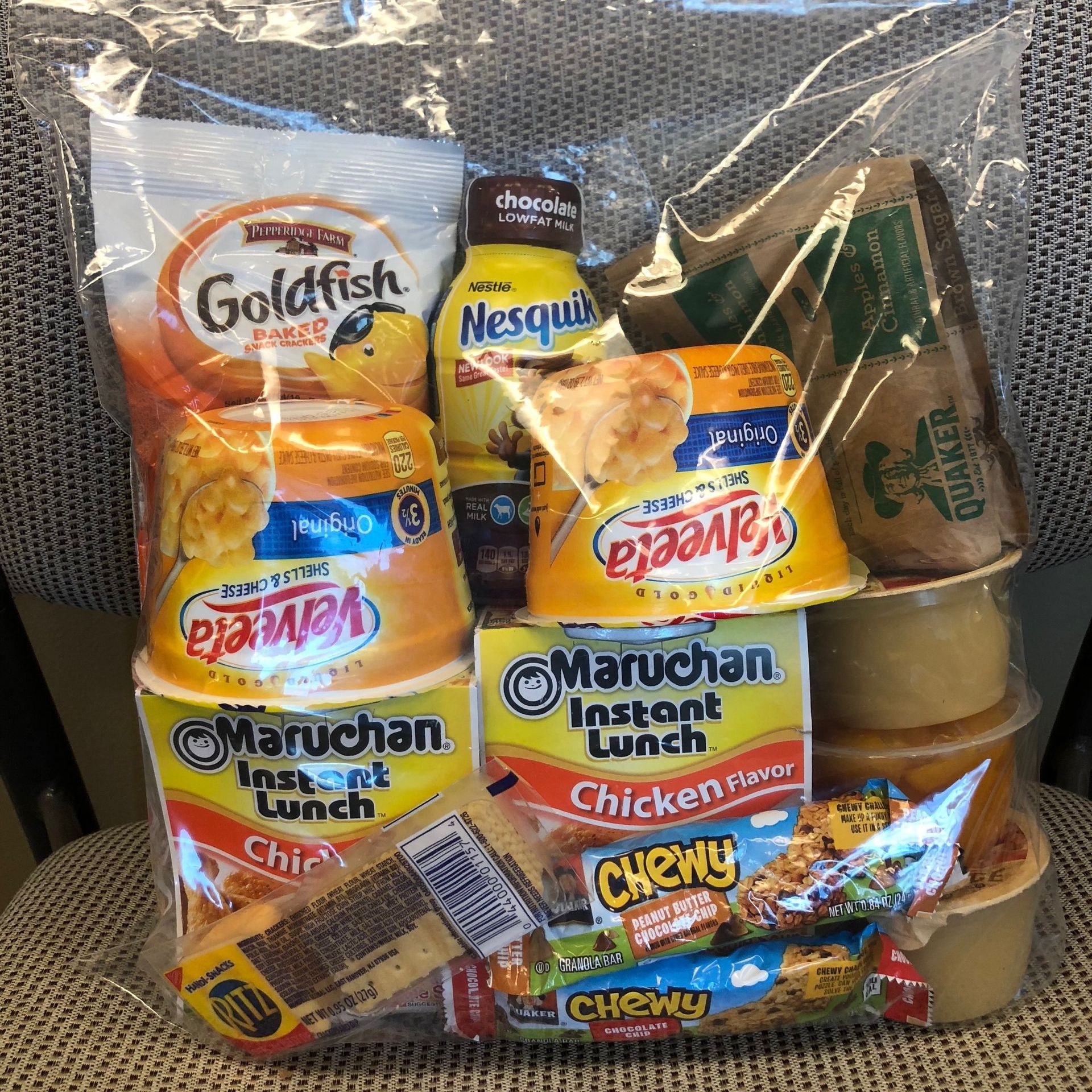 A bag of snacks including goldfish , maruchan instant lunch chicken , and chewy candy.