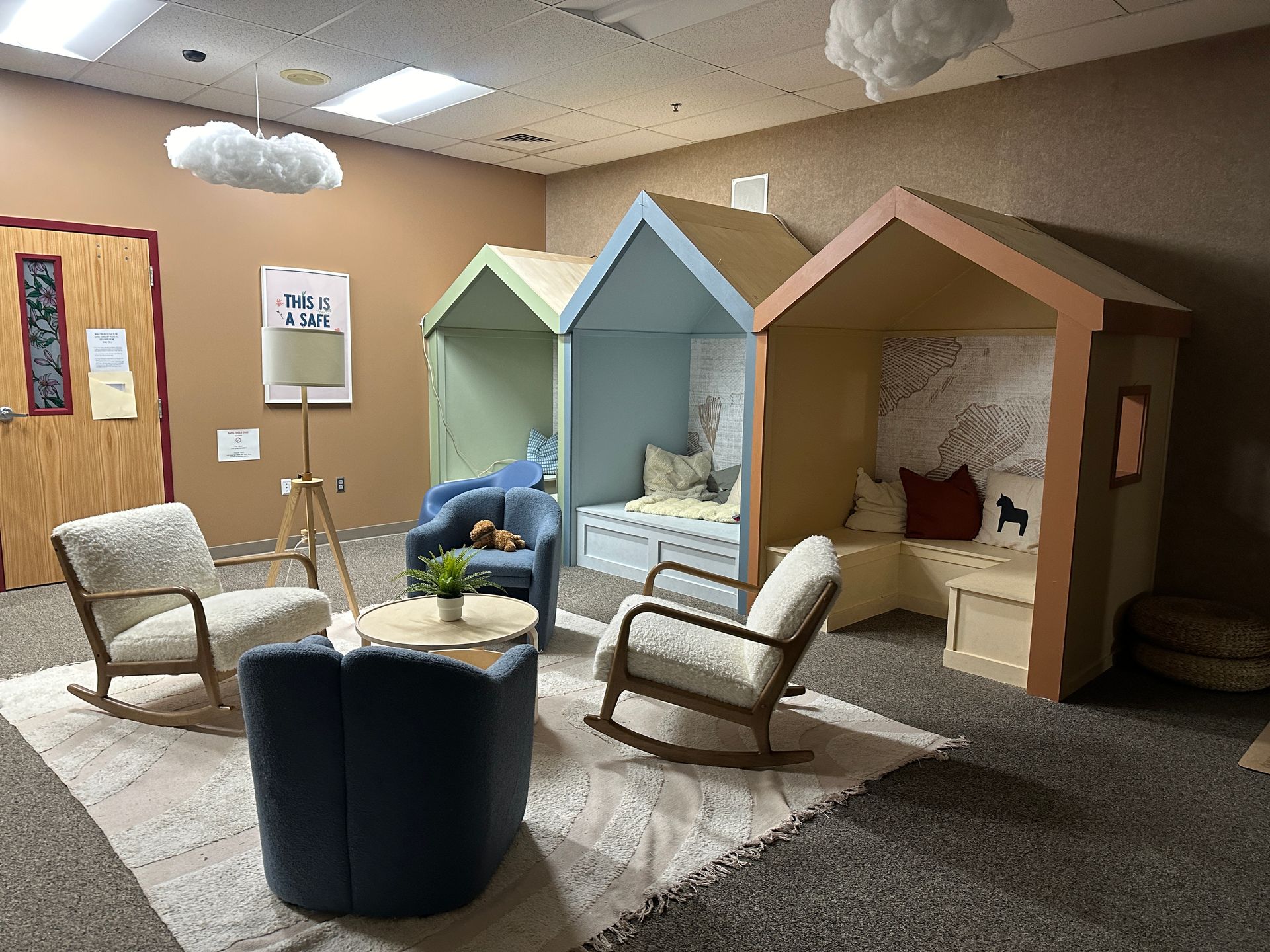 A room with rocking chairs , a table , and a couch in the shape of a house.