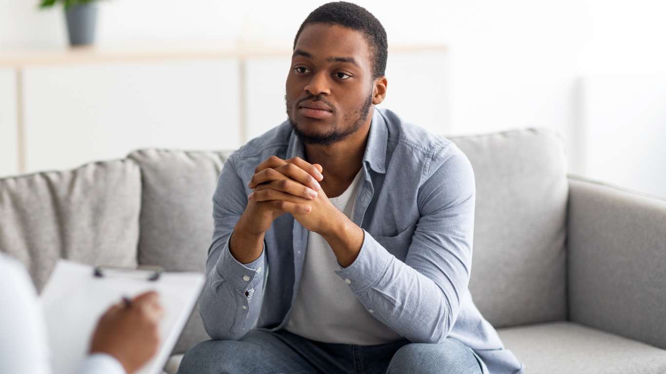 A man with a beard is standing in a field with his eyes closed.