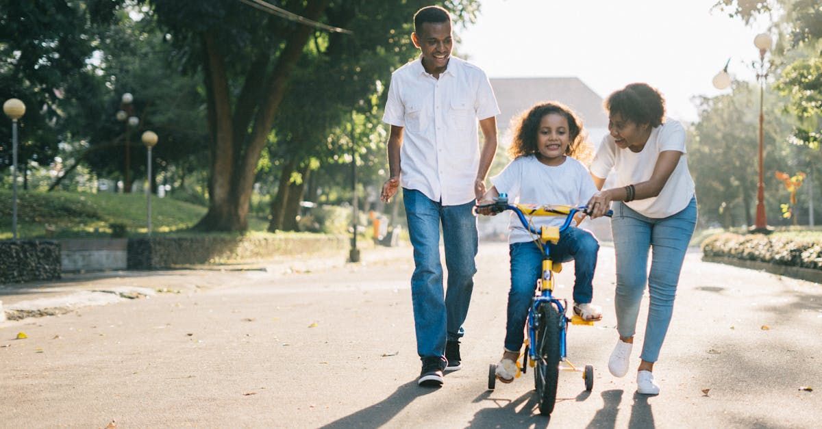 A family is walking down a street while a child is riding a bike.