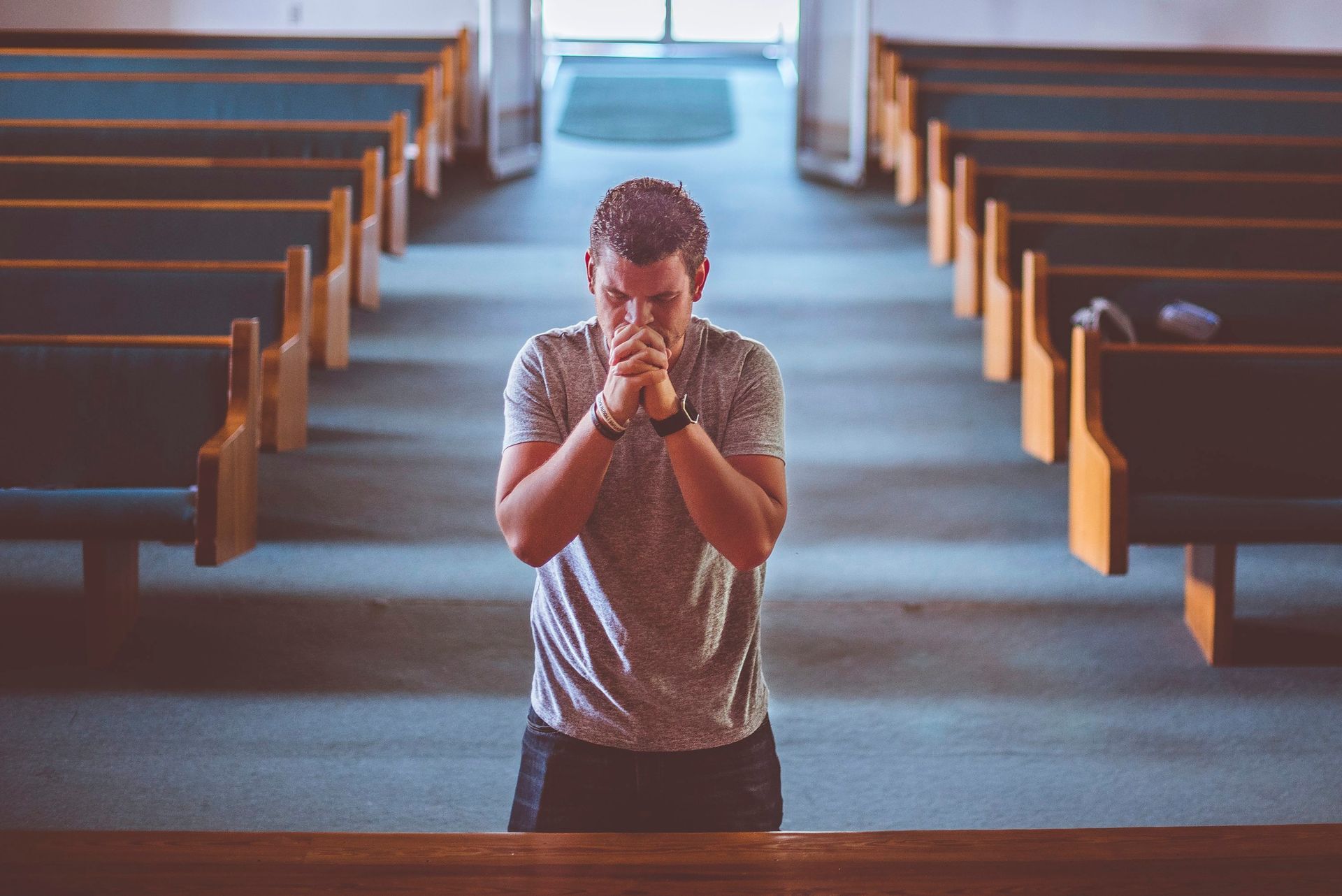 A man is praying in an empty church.