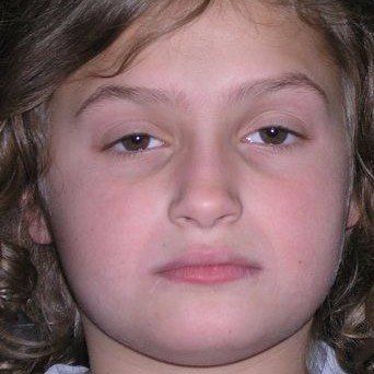 A close up of a young girl 's face with curly hair.