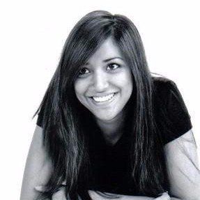 A woman with long hair is smiling in a black and white photo.