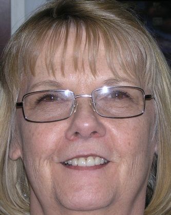 A close up of a woman wearing glasses and smiling.