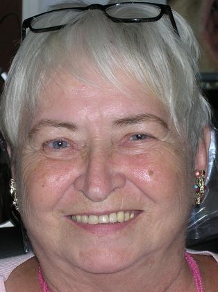 A close up of a woman wearing glasses and smiling.