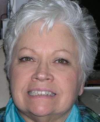 A close up of a woman 's face with gray hair and a blue shirt.