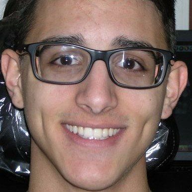 A young man wearing glasses is smiling for the camera