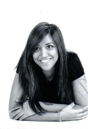 A black and white photo of a woman laying down with her arms crossed and smiling.