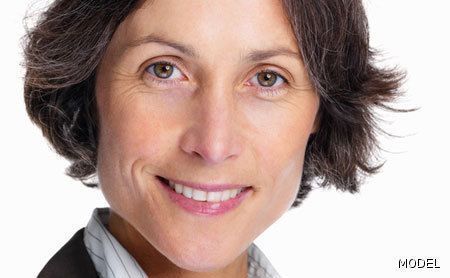 A close up of a woman 's face smiling on a white background.