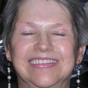 A close up of a woman 's face smiling with her eyes closed.