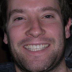 A close up of a man 's face with a beard smiling.