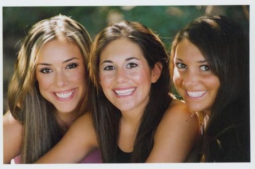 Three women are posing for a picture and smiling for the camera