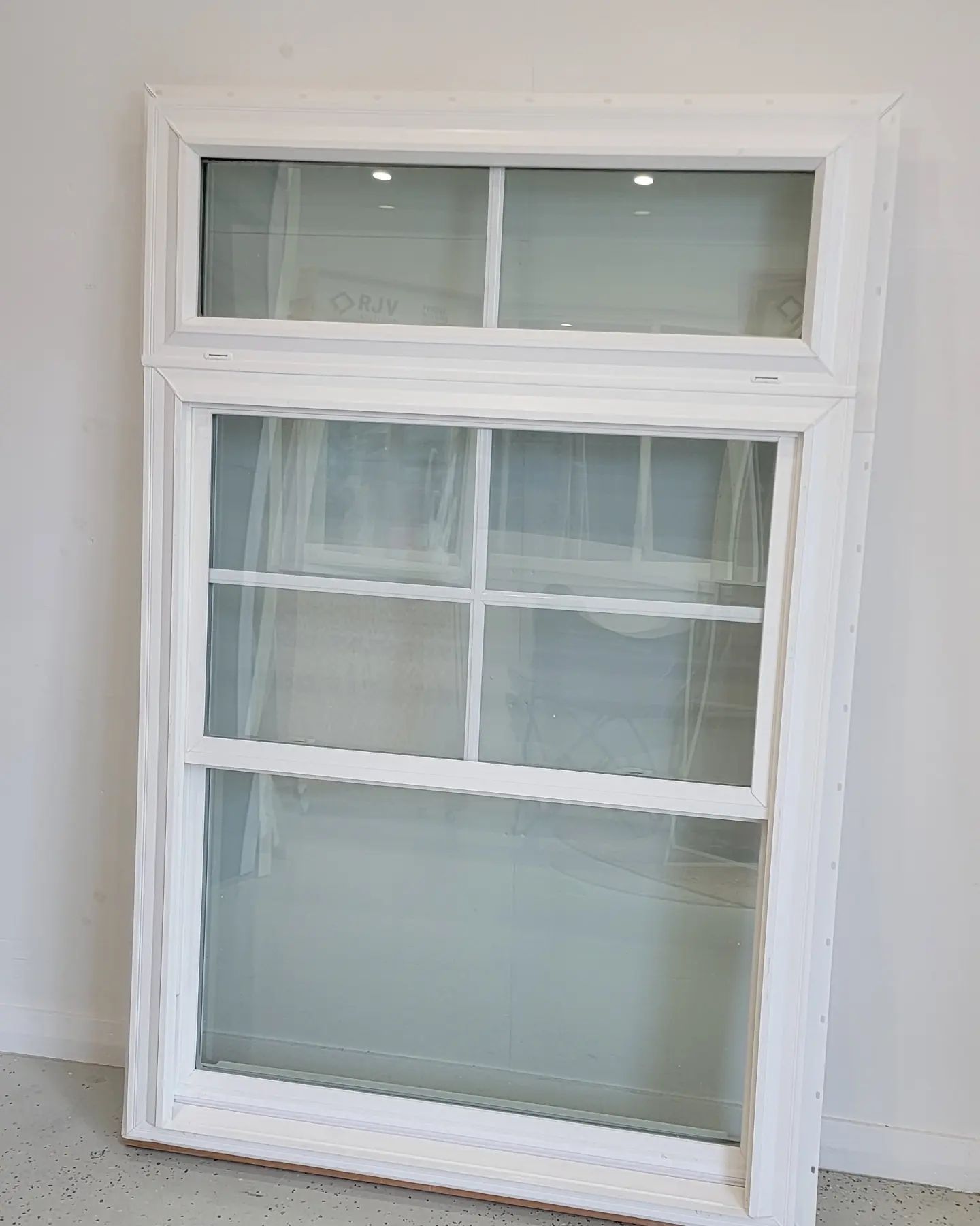 White, rectangular, double-hung window with multiple panes set against a light background.