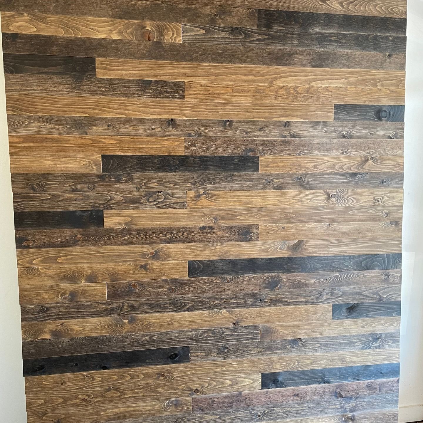 Wooden wall paneling composed of various shades of brown and gray planks.