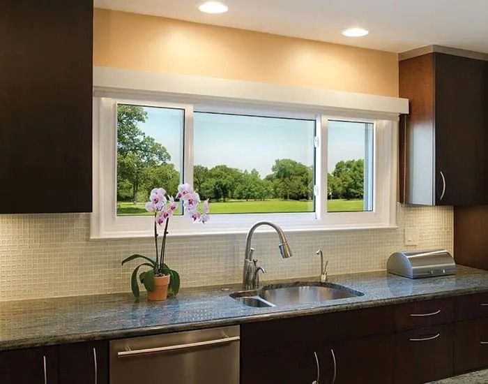 Kitchen with a view: A sink and countertops are in front of a large window overlooking a green landscape.