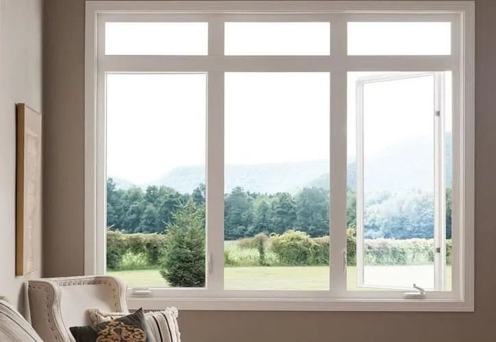 A white-framed window with an open casement window displaying a view of a green landscape.