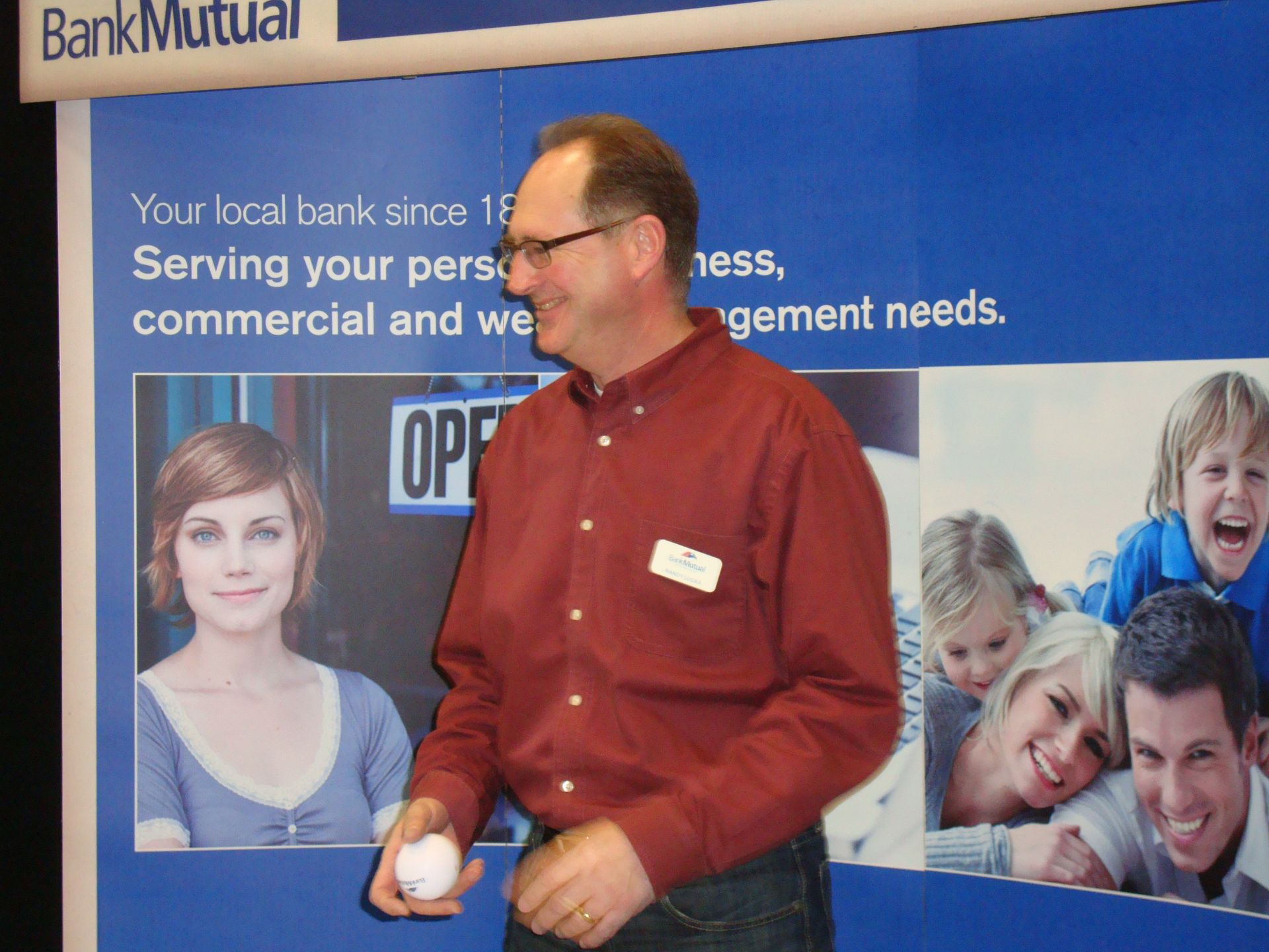 A man stands in front of a bank mutual sign