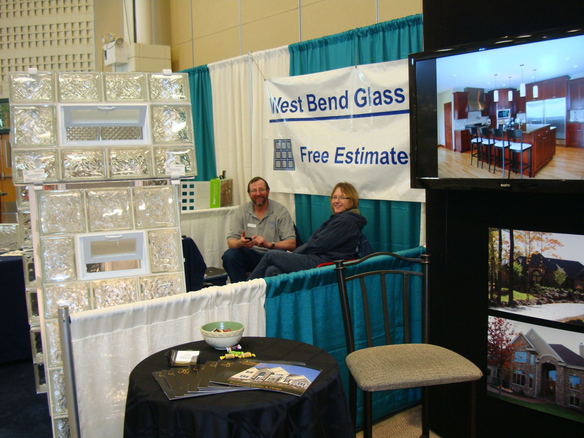 Two people sit at a table in front of a west bend glass sign