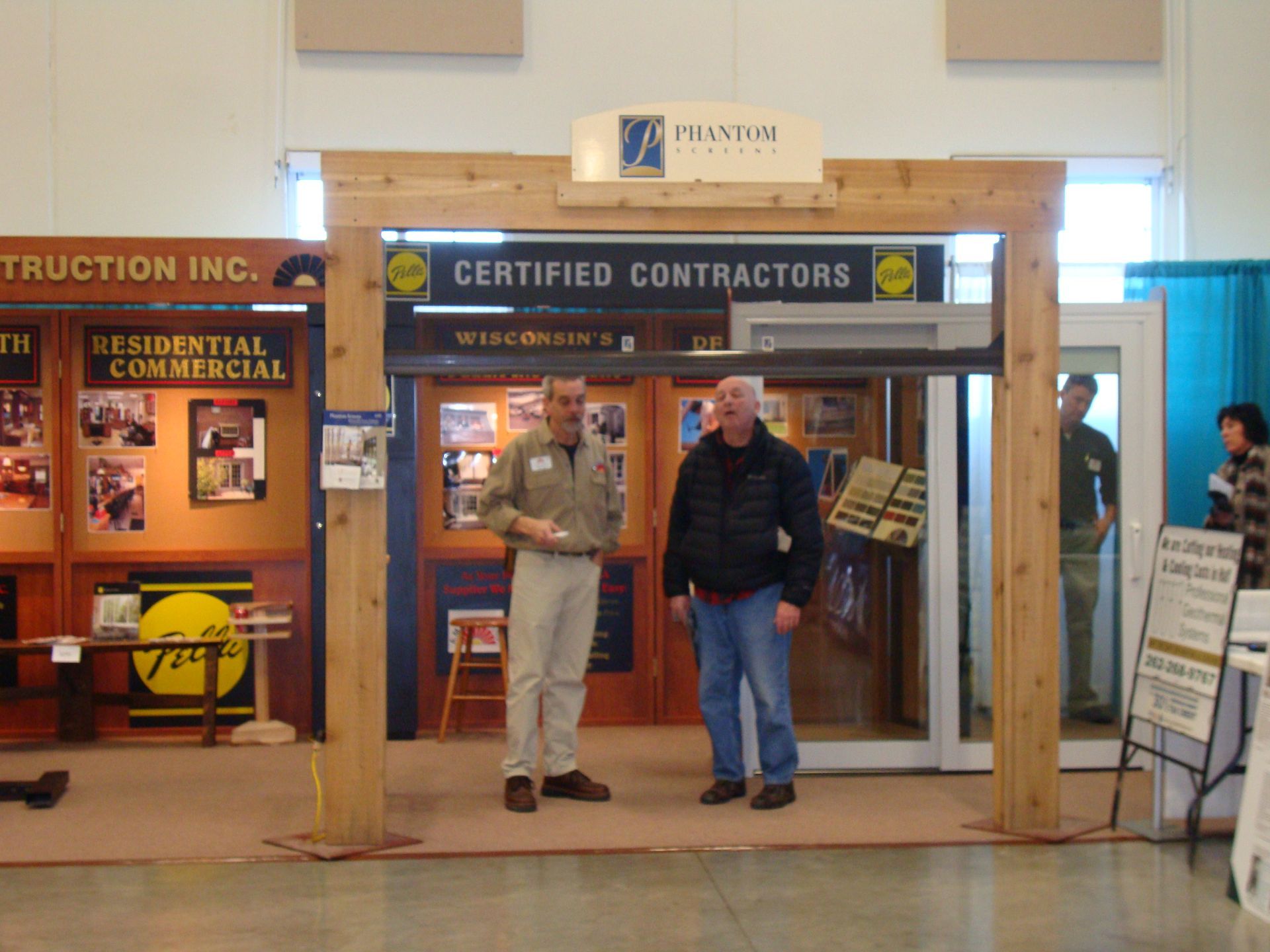 Two men standing under a sign that says certified contractors