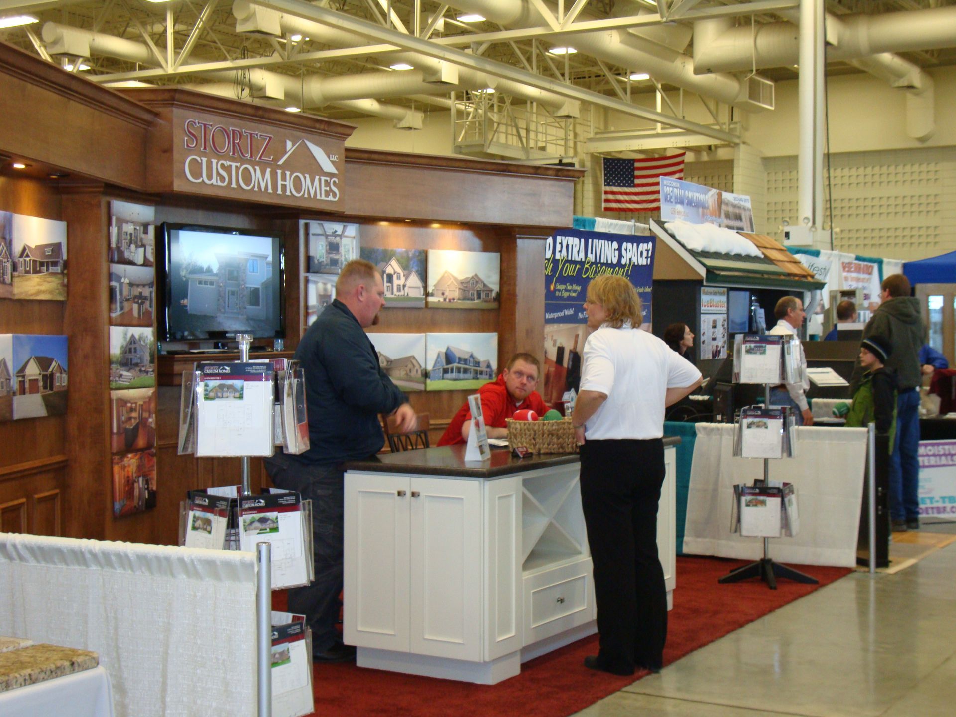 A group of people standing around a booth that says scotts custom homes