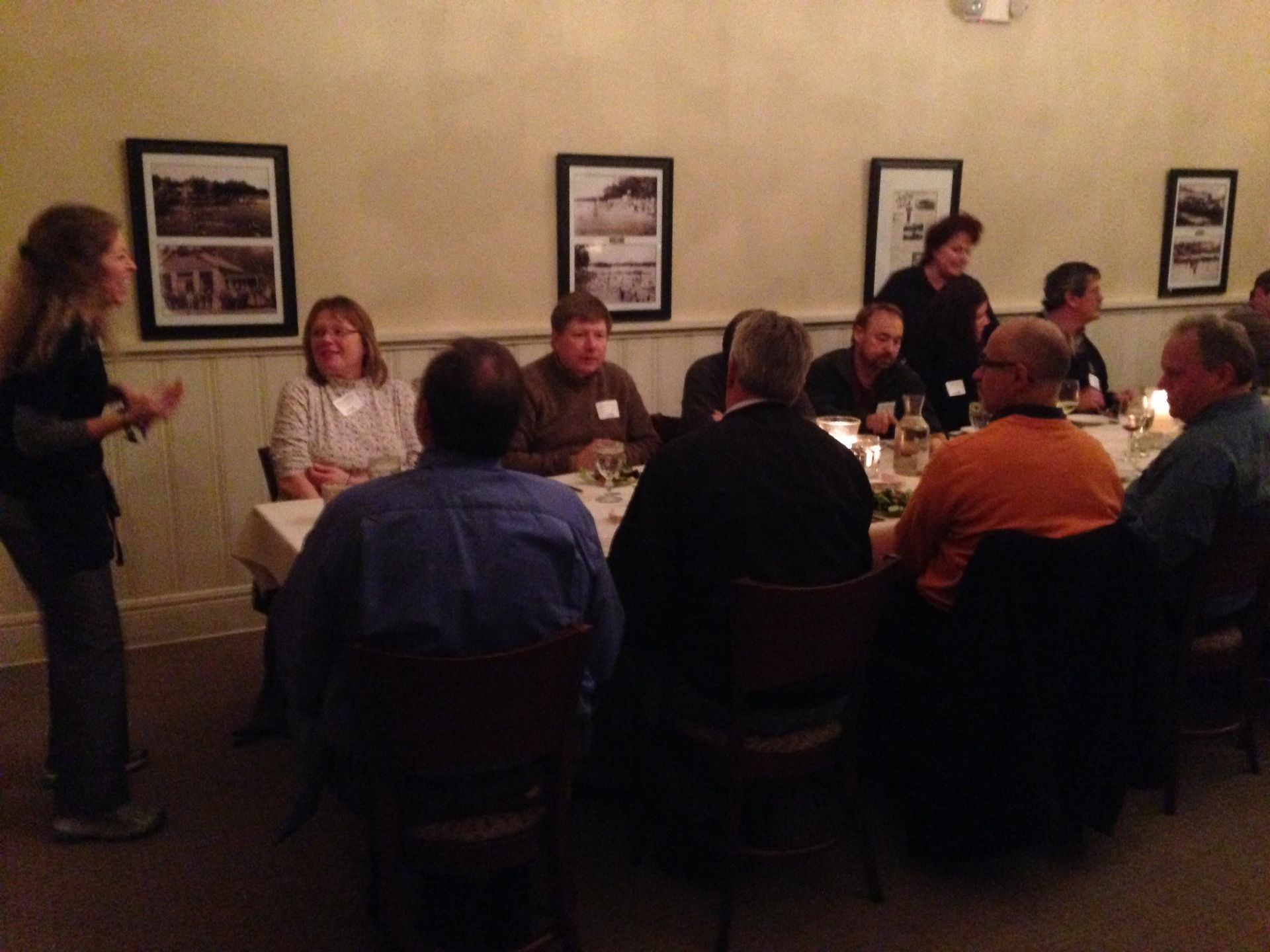 A woman stands in front of a group of people sitting at tables