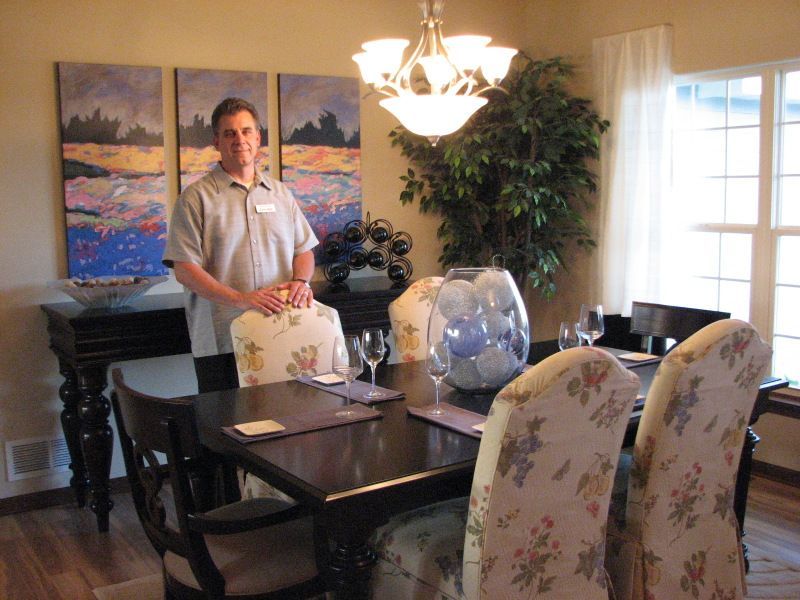 A man stands in a dining room with a table and chairs