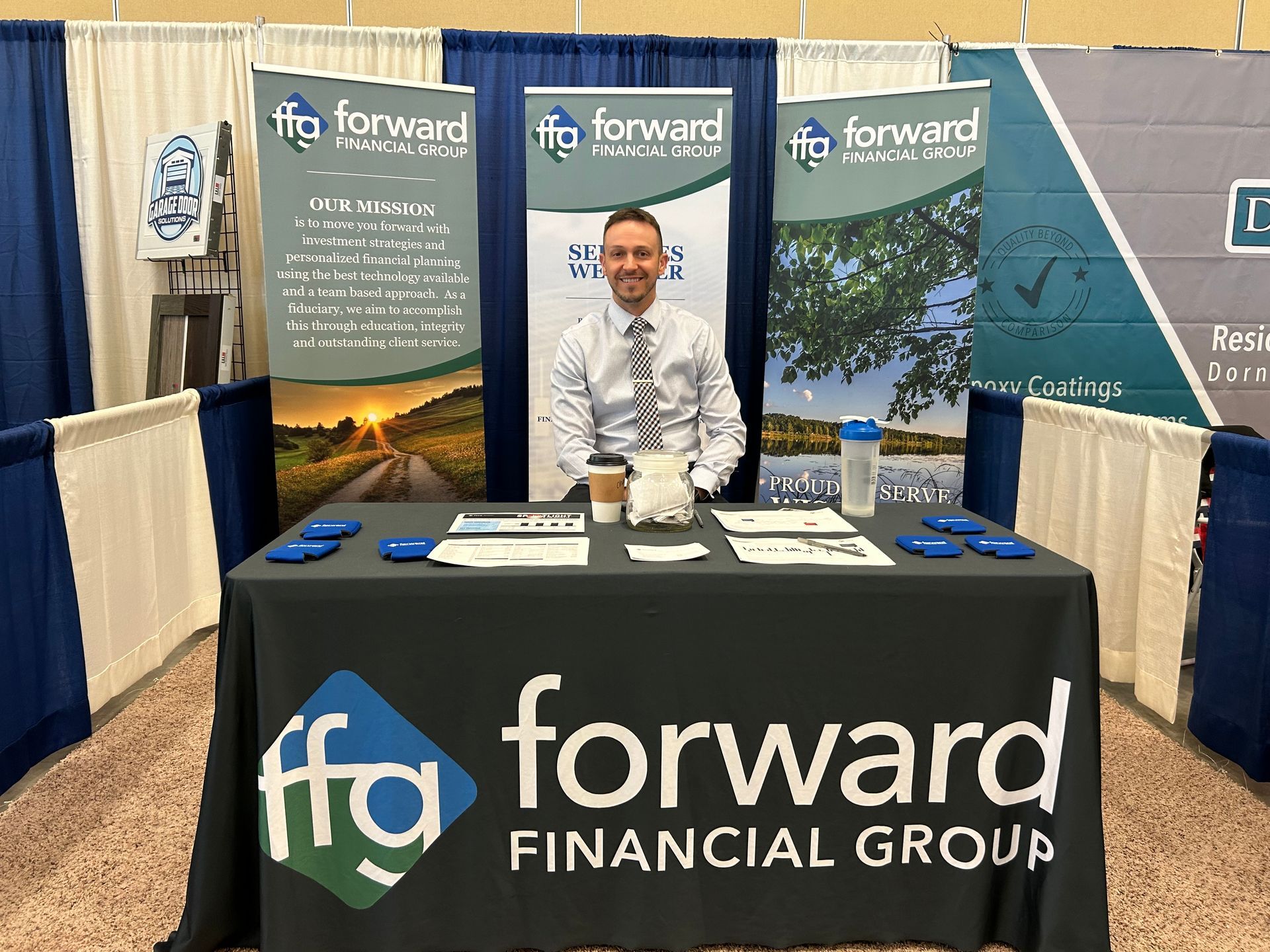A man is sitting at a table at a forward financial group booth.