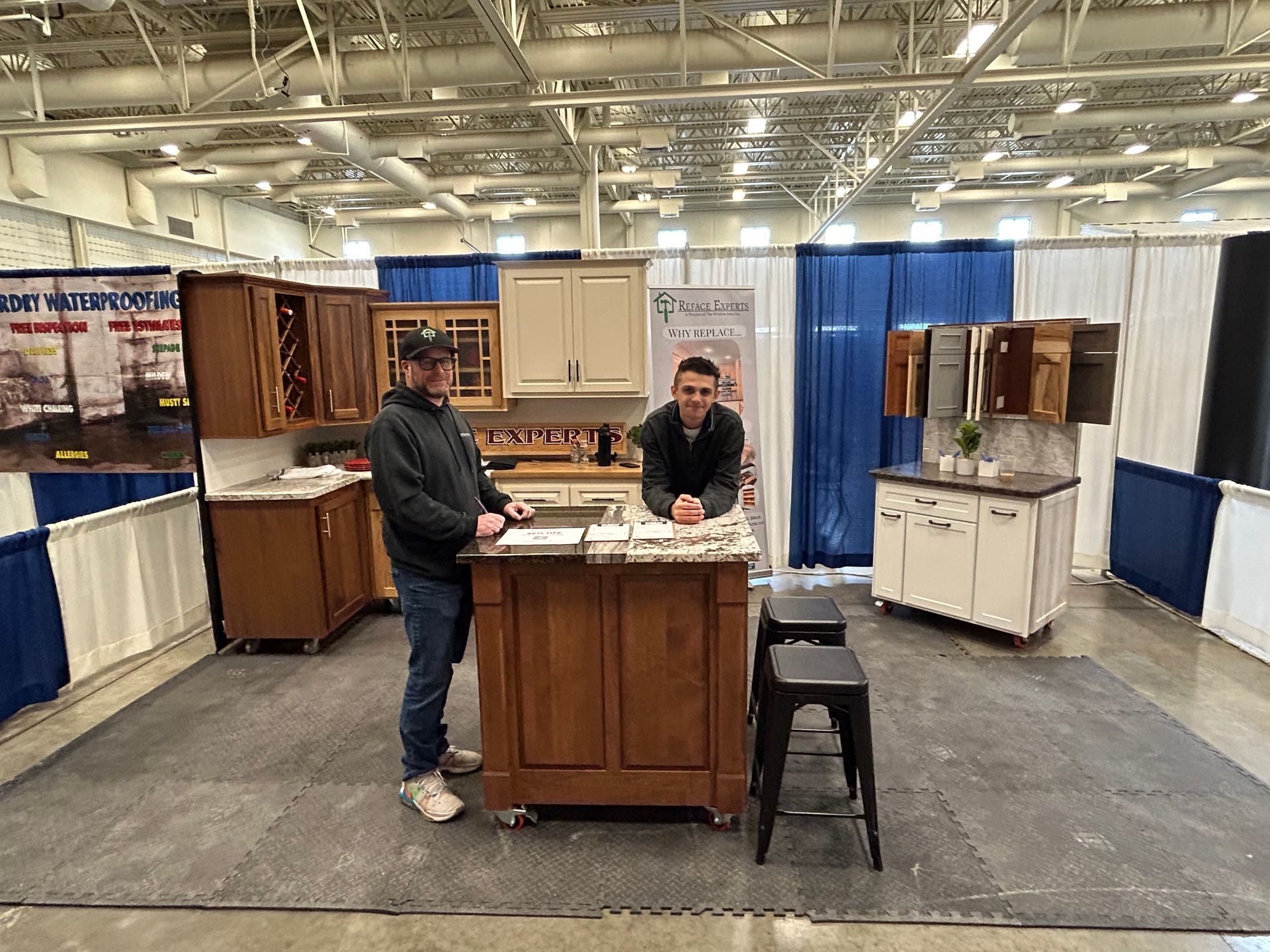 Two men are standing in front of a kitchen island.