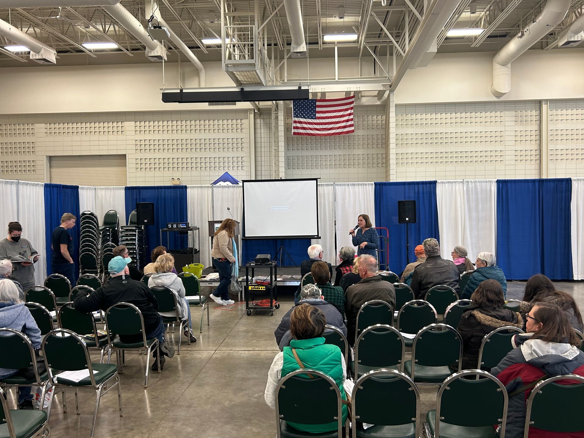 A group of people are sitting in chairs in front of a projector screen.