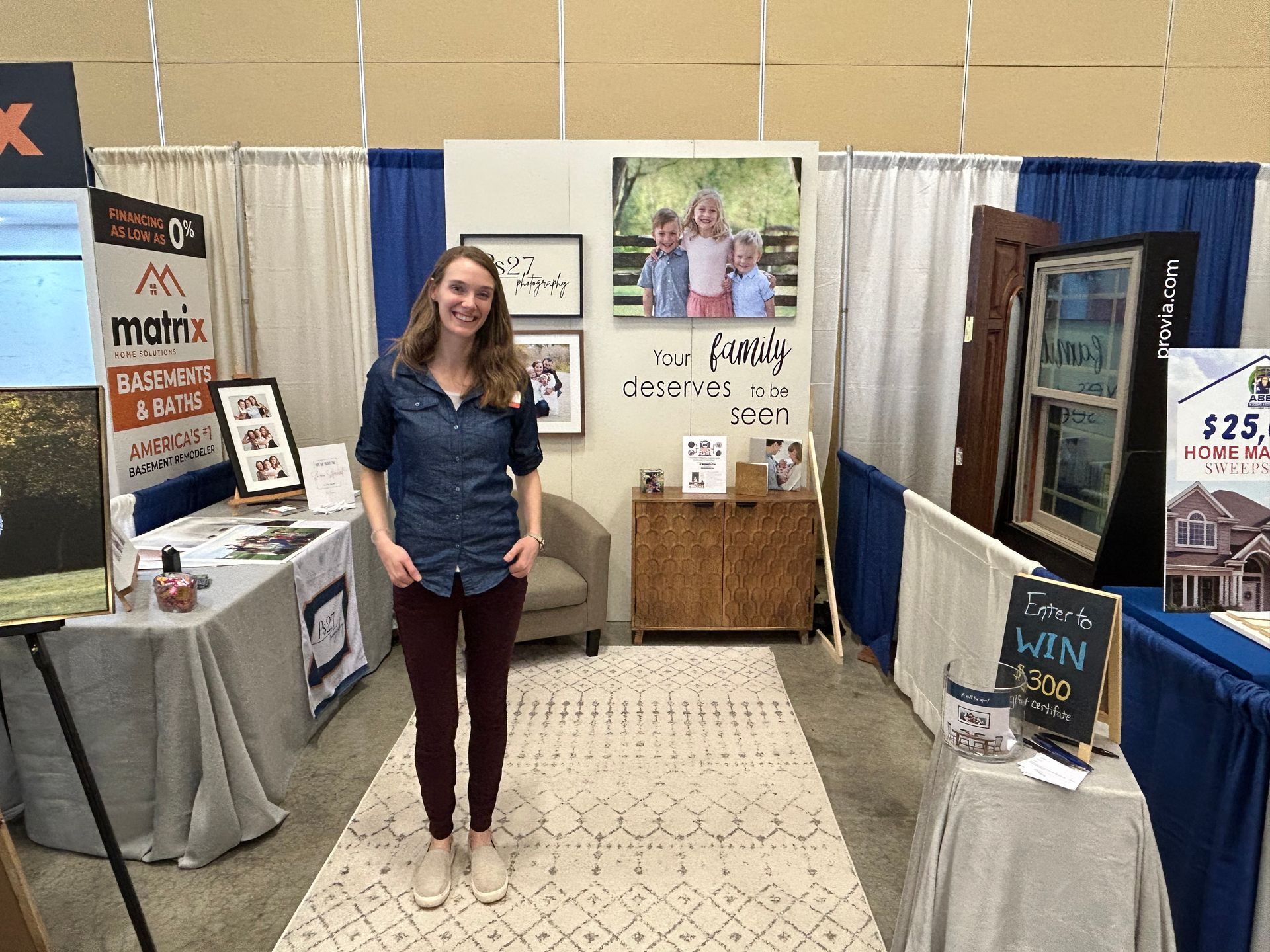 A woman is standing in front of a booth at a real estate show.